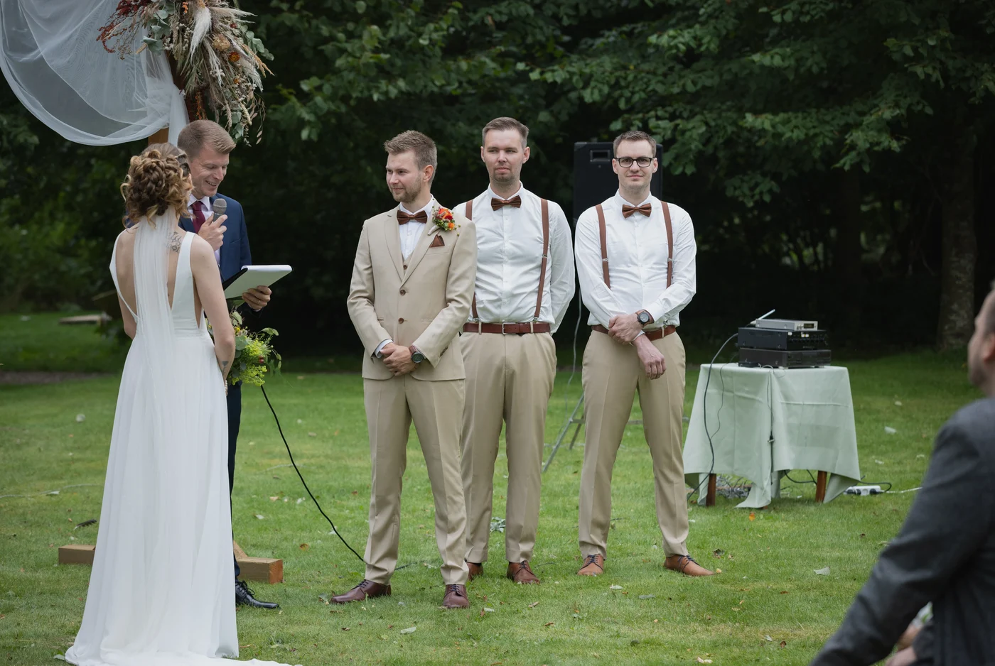 Bruidegom en getuigen in maatpakken bij de ceremonie in de tuin